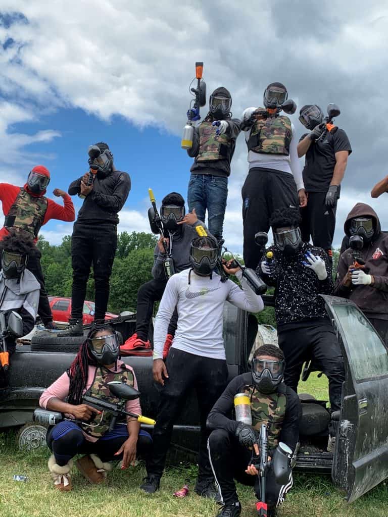 paintball players standing on car on field